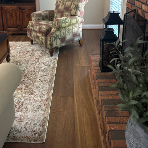 A patterned armchair on hardwood floors next to a fireplace with decorative lanterns.